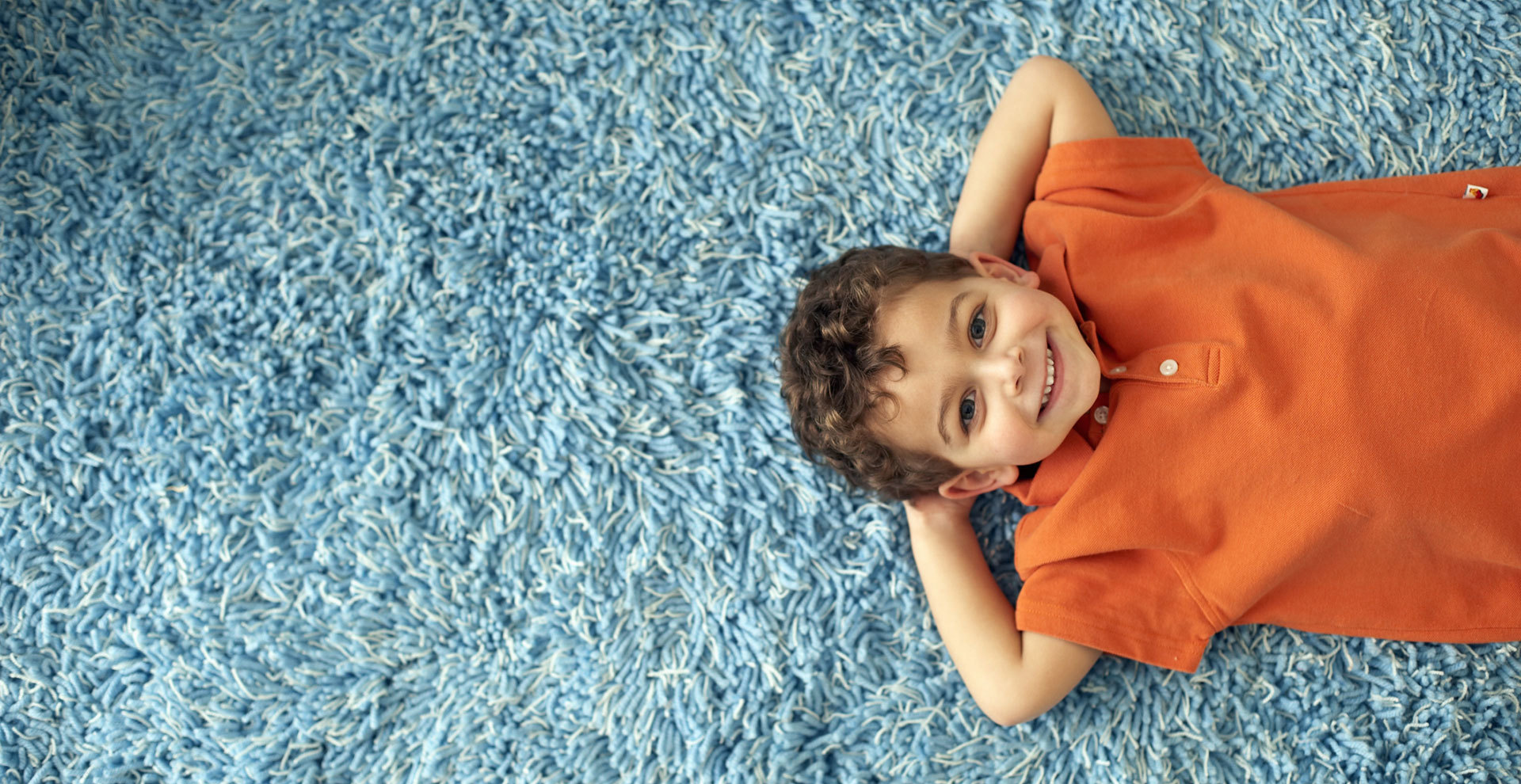 Young Boy Laying on Blue Carpet