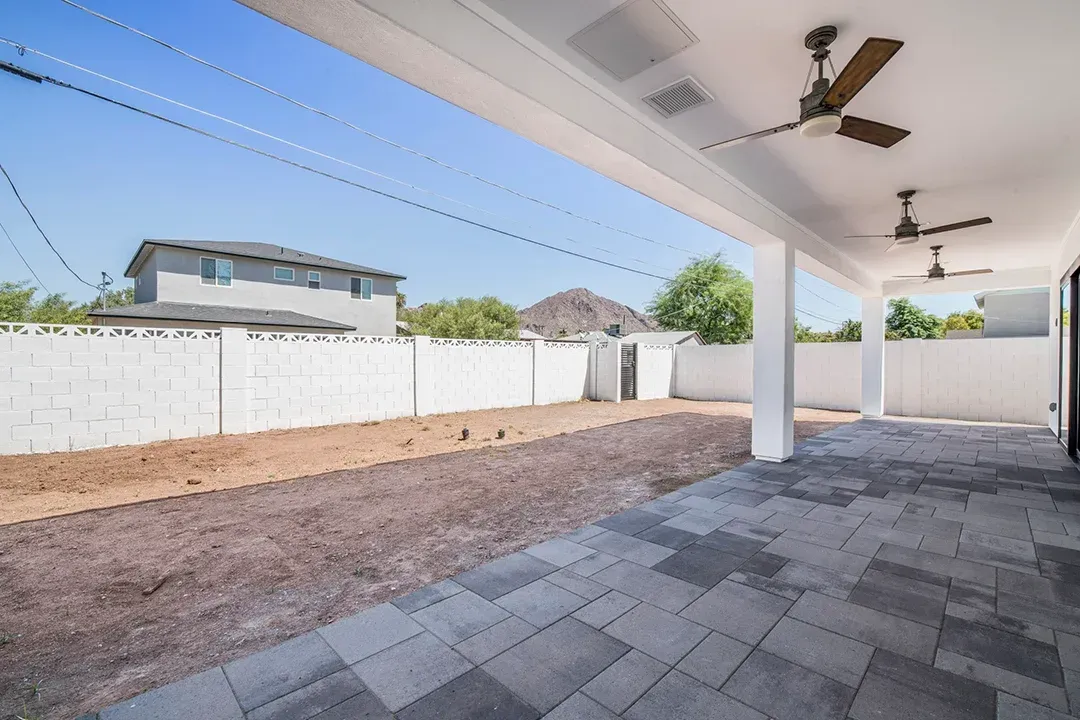 A patio with a ceiling fan and a fence in the background.