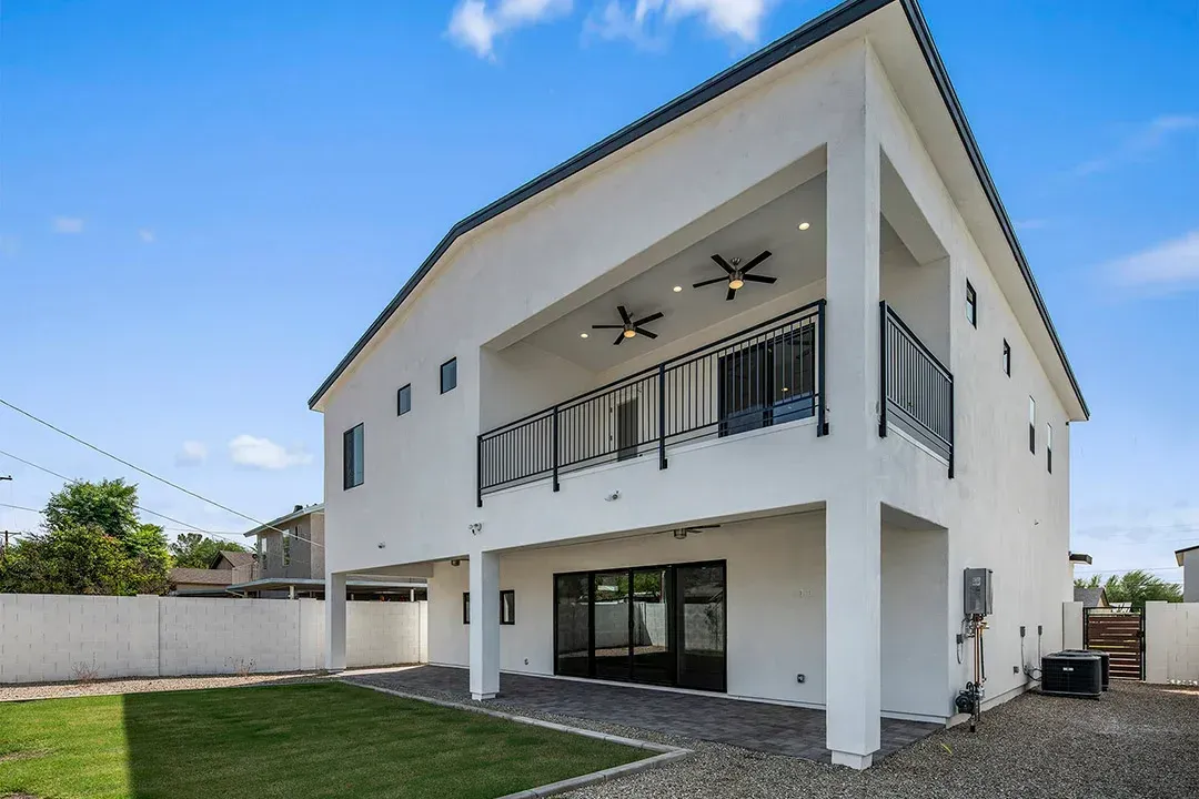 A large white house with a balcony and a large lawn in front of it.