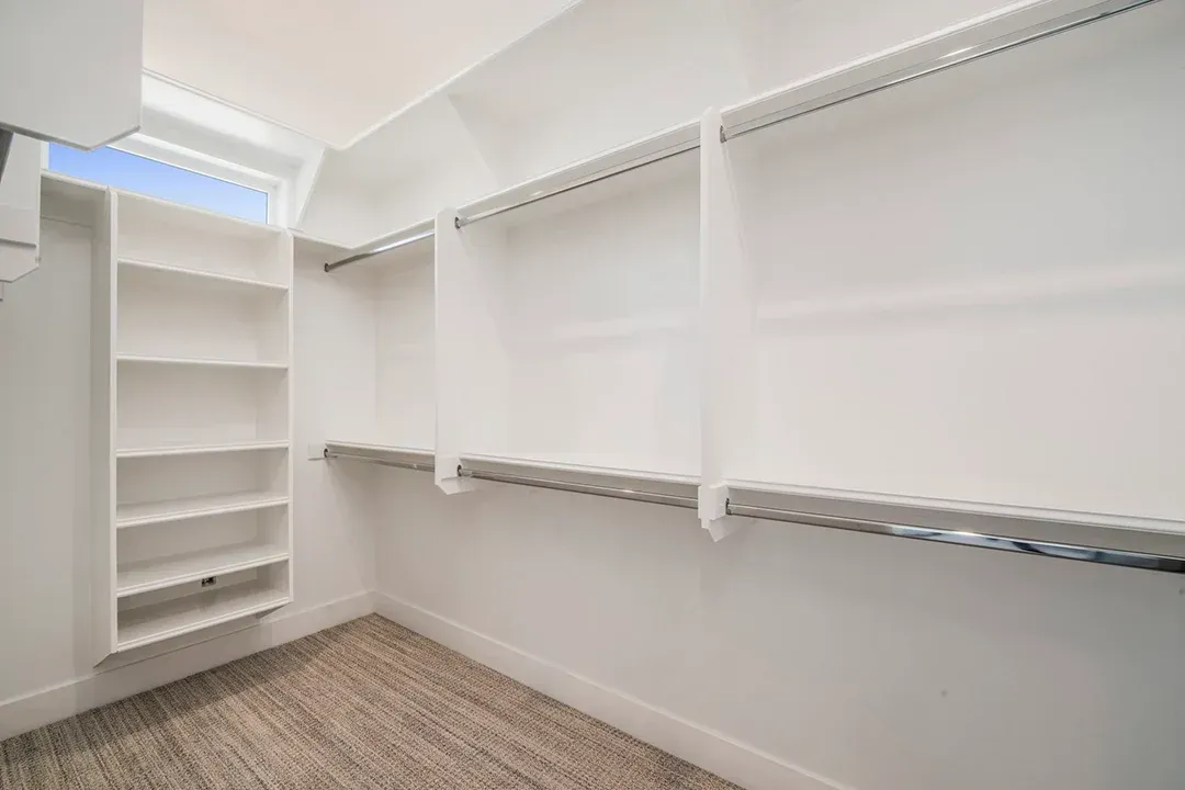 A walk in closet with lots of shelves and clothes racks.