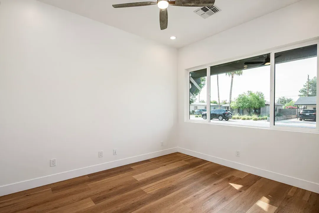 An empty room with hardwood floors and a ceiling fan.