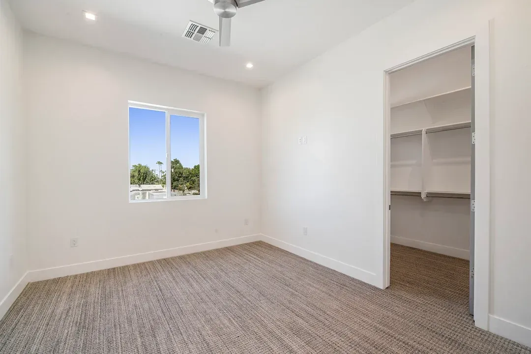 An empty bedroom with a walk in closet and a window.