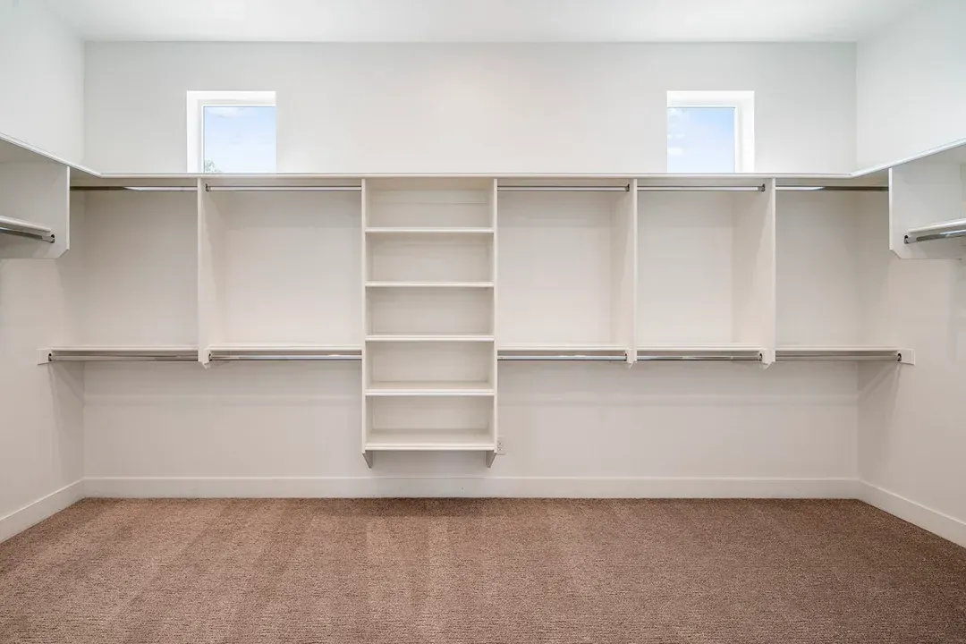 An empty walk in closet with lots of shelves and clothes racks.