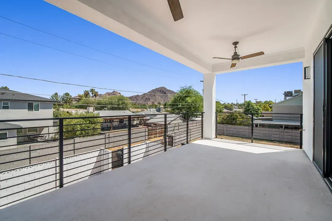 A balcony with a ceiling fan and a view of a city.