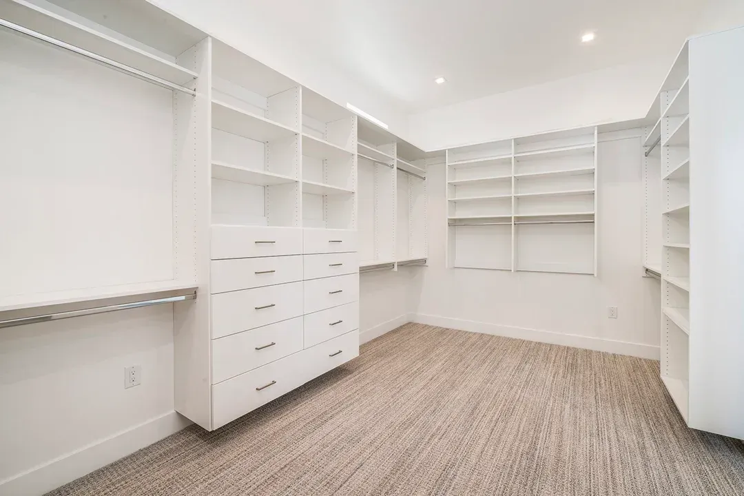 An empty walk in closet with lots of shelves and drawers.