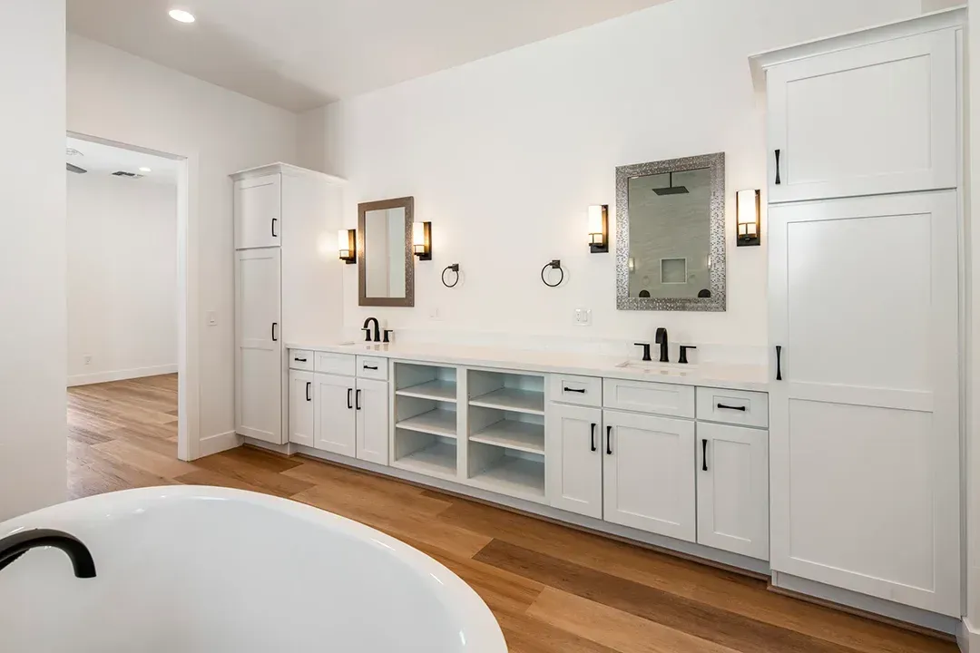 A bathroom with a bathtub , sink , mirror and cabinets.