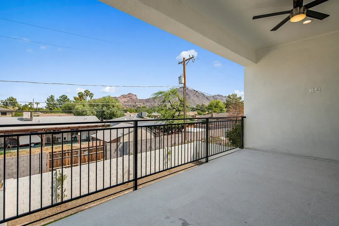 An empty balcony with a railing and a ceiling fan