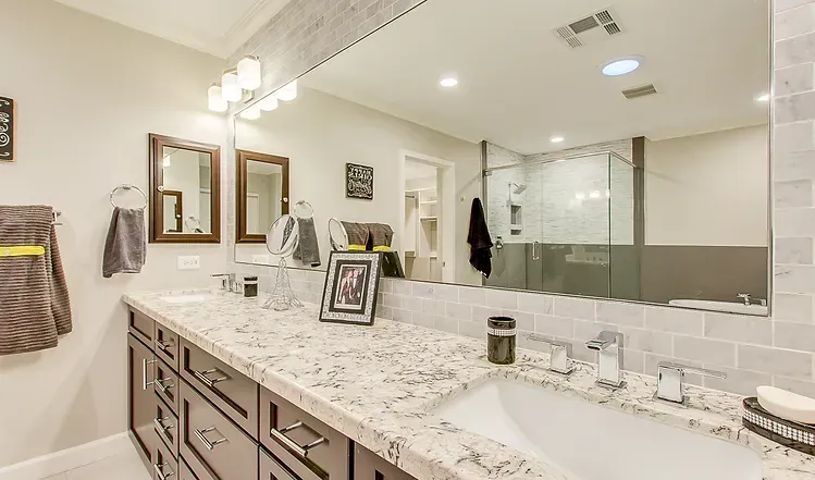 A bathroom with two sinks , a large mirror and a walk in shower.