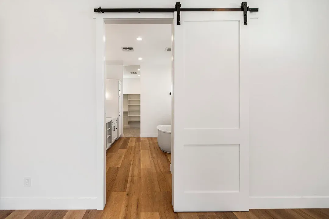 A white sliding barn door is open to a bathroom.