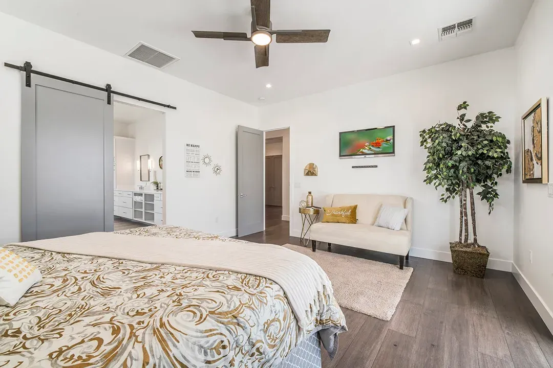 A bedroom with a bed , couch , and ceiling fan.