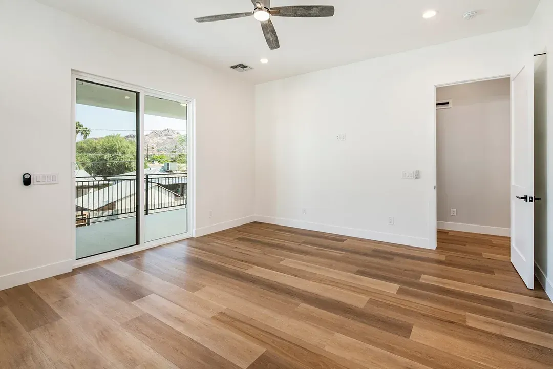 An empty bedroom with hardwood floors and a ceiling fan.