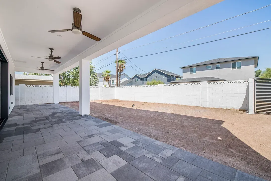 A patio with a ceiling fan in the backyard of a house.