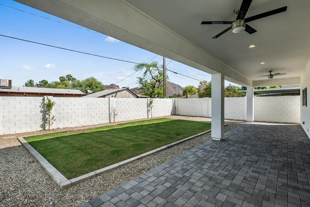 There is a ceiling fan in the backyard of a house.