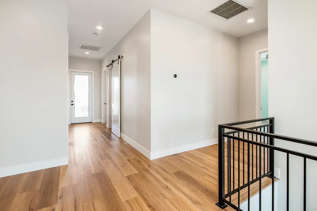 A hallway with hardwood floors and white walls in a house.