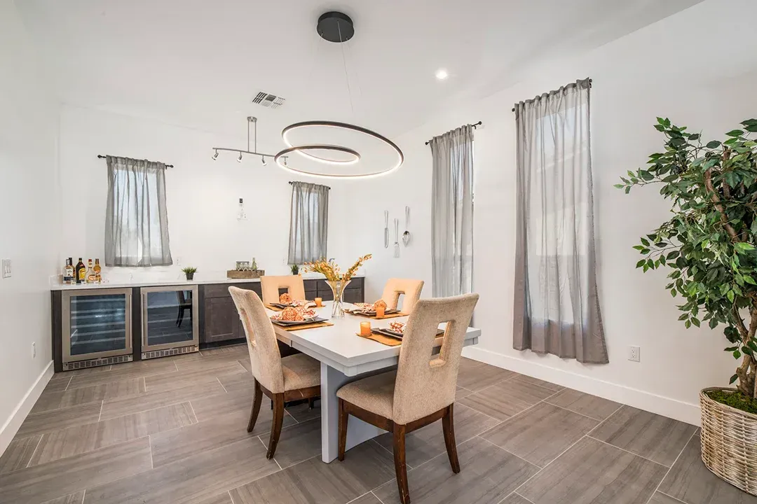 A dining room with a table and chairs and a plant.