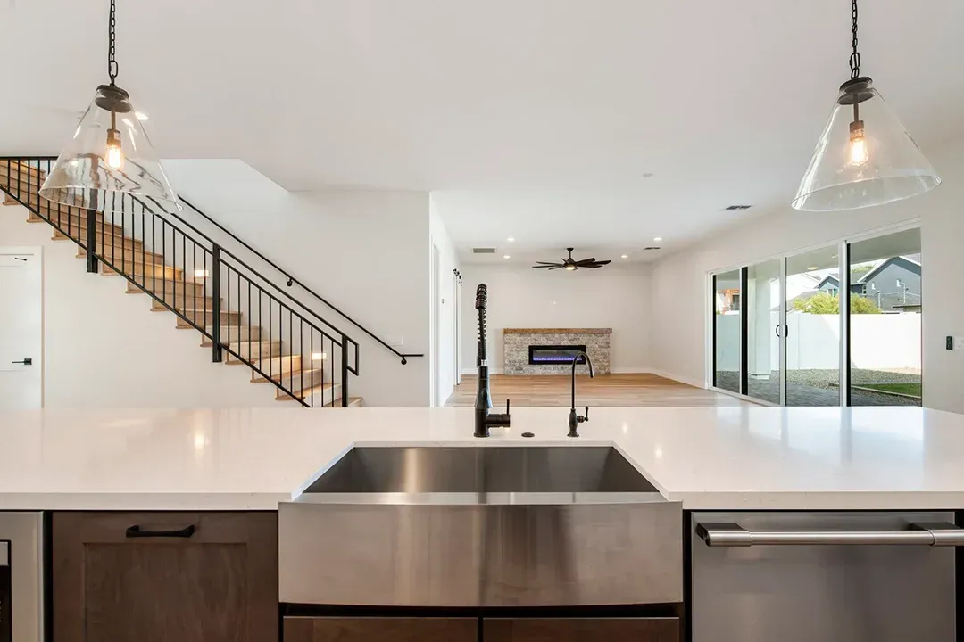 A kitchen with a sink and stairs in the background.