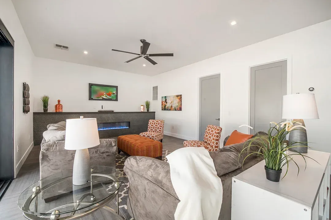 A living room with a couch , chairs , lamps and a ceiling fan.