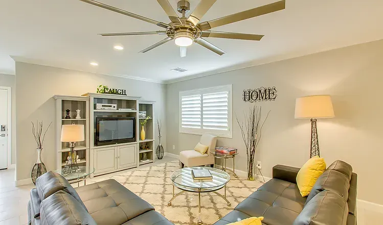 A living room with a ceiling fan , a couch , and a television.