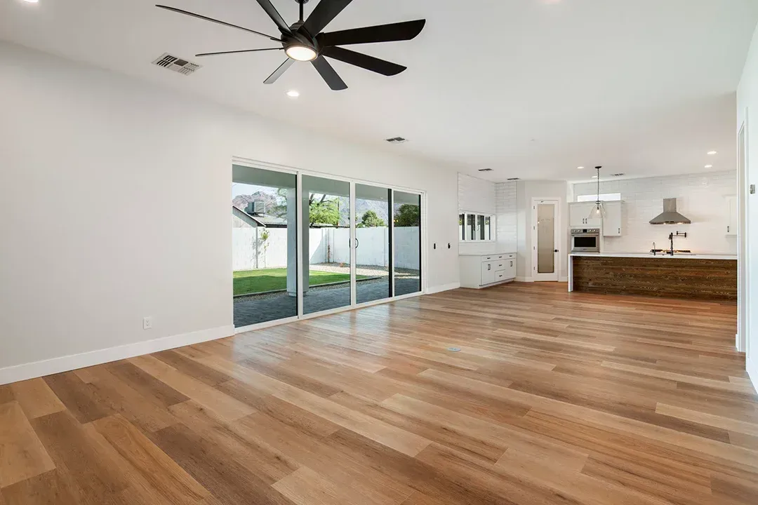 An empty living room with hardwood floors and a ceiling fan.