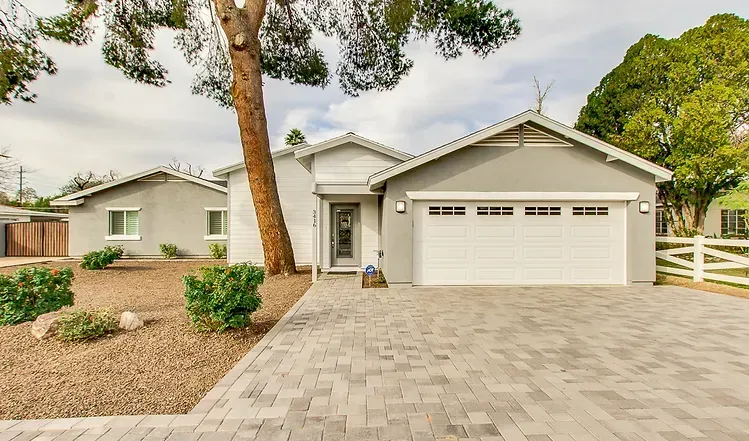 A house with a white garage door and a brick driveway