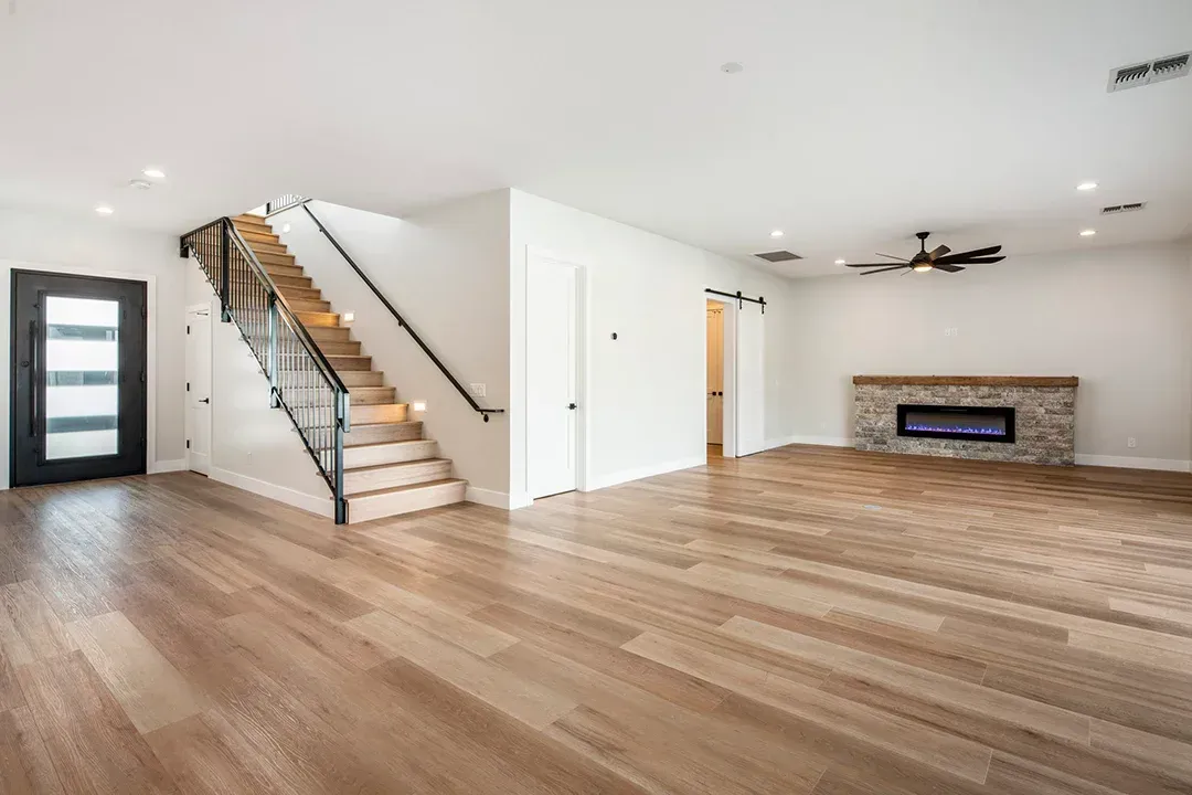 A living room with hardwood floors , stairs and a fireplace.