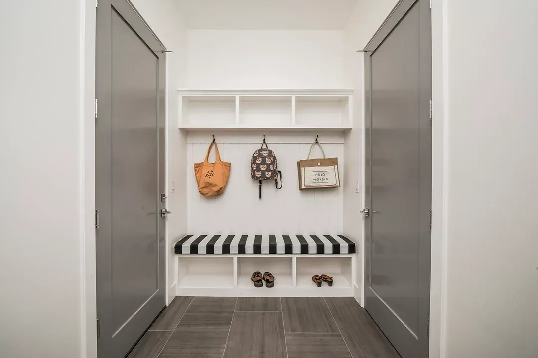 A hallway with a bench and a striped cushion.