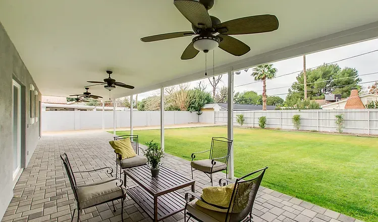 A patio with a table and chairs and a ceiling fan.