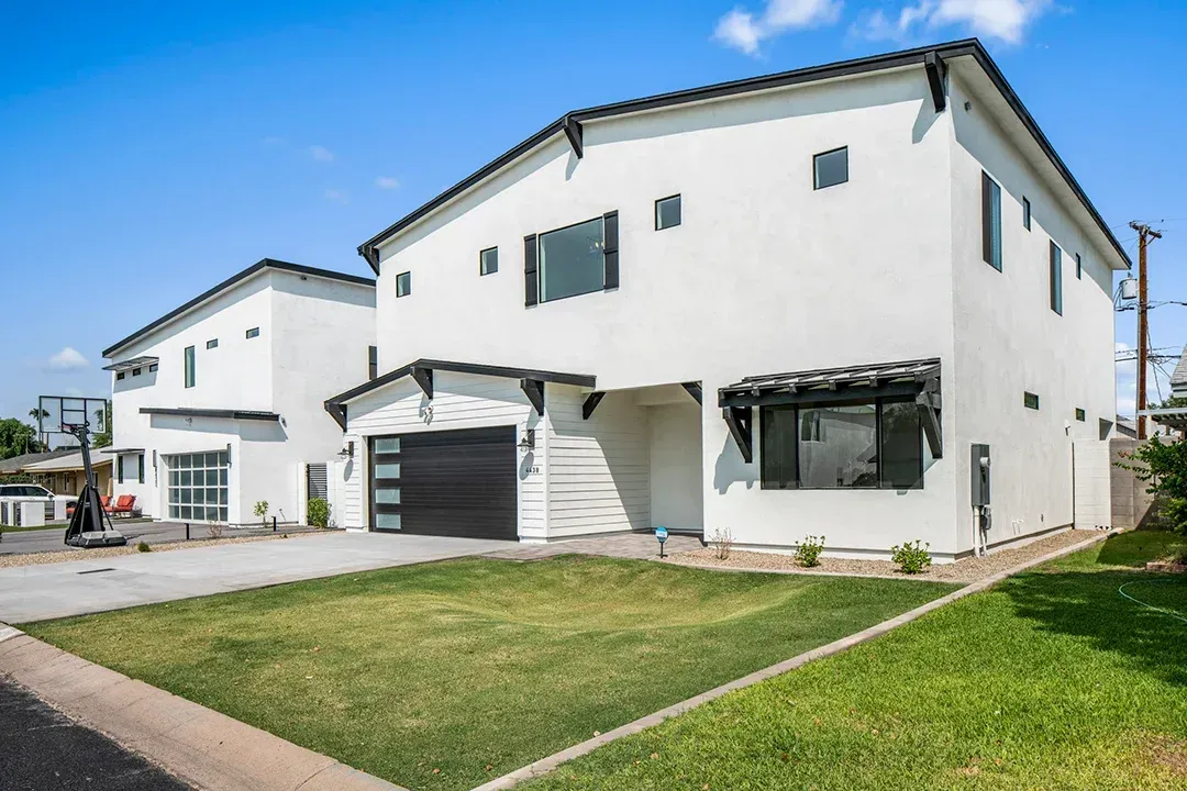 A white house with a black garage door is for sale.