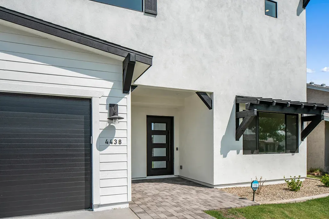 A white house with a black garage door and a black door.