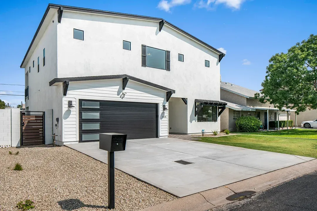 A white house with a black garage door and a black mailbox