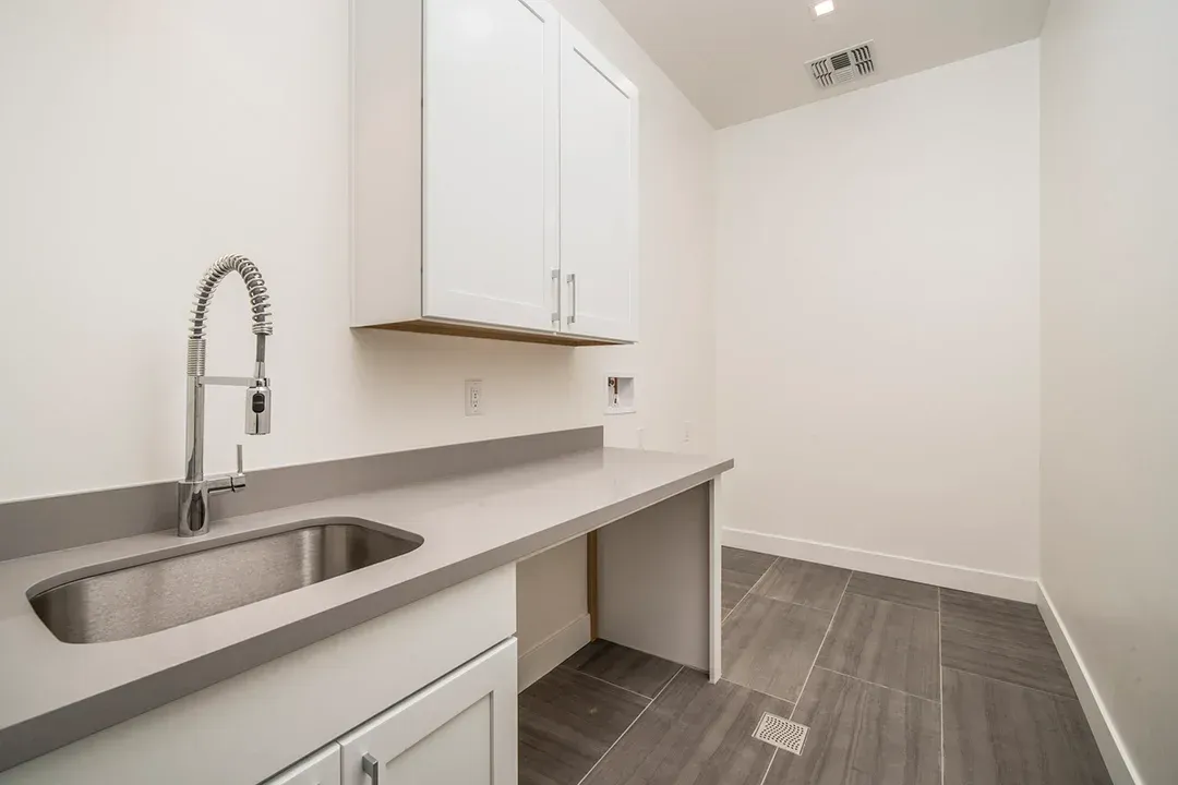 A kitchen with a sink , cabinets and a faucet.