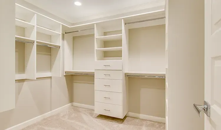 A walk in closet with lots of shelves and drawers.