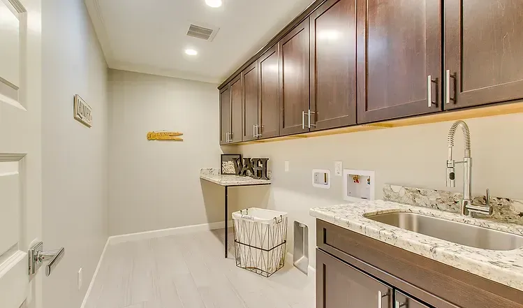 A laundry room with a sink , cabinets , and granite counter tops.