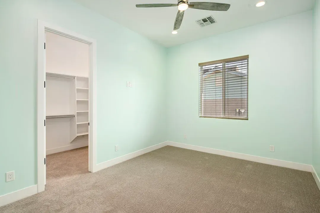 An empty bedroom with a ceiling fan and a window.