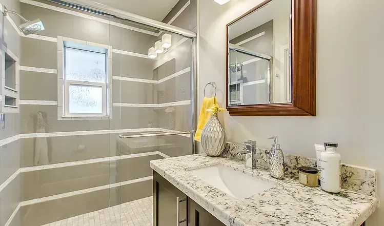 A bathroom with a sink , mirror and walk in shower.