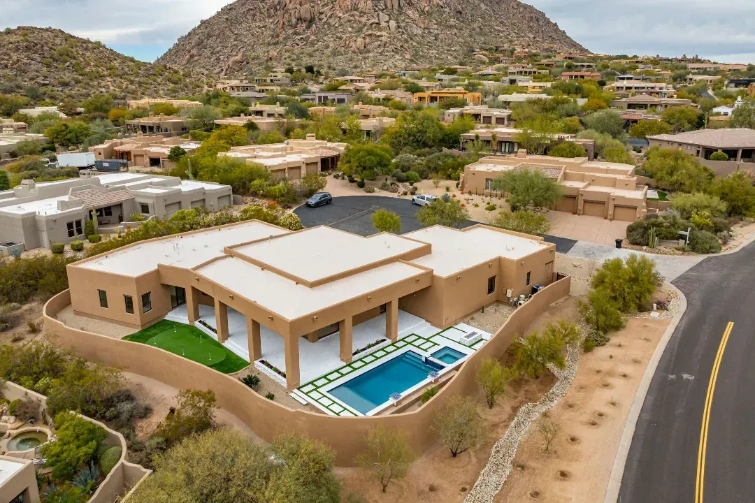 An aerial view of a large house with a pool in the desert.