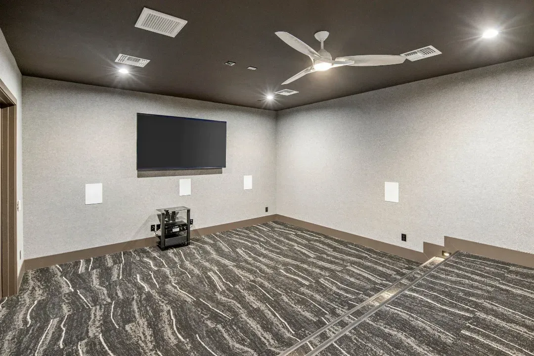 A home theater with a flat screen tv and a ceiling fan.