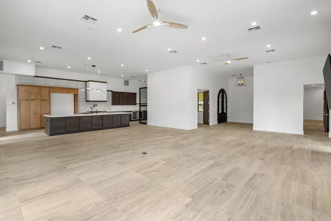 A large empty room with hardwood floors and a ceiling fan.