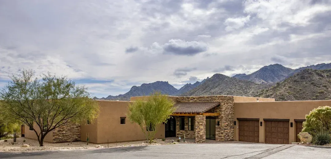 A large house in the desert with mountains in the background.