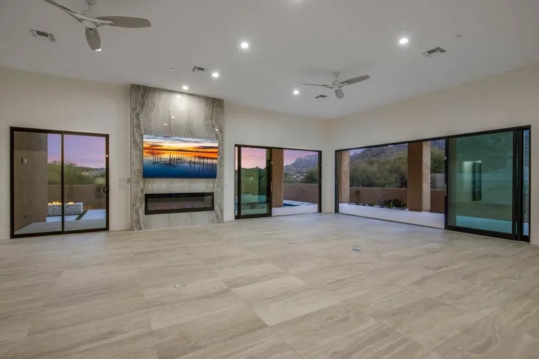 An empty living room with a fireplace and sliding glass doors