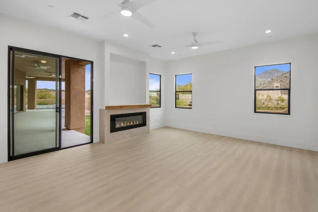 An empty living room with a fireplace and sliding glass doors.