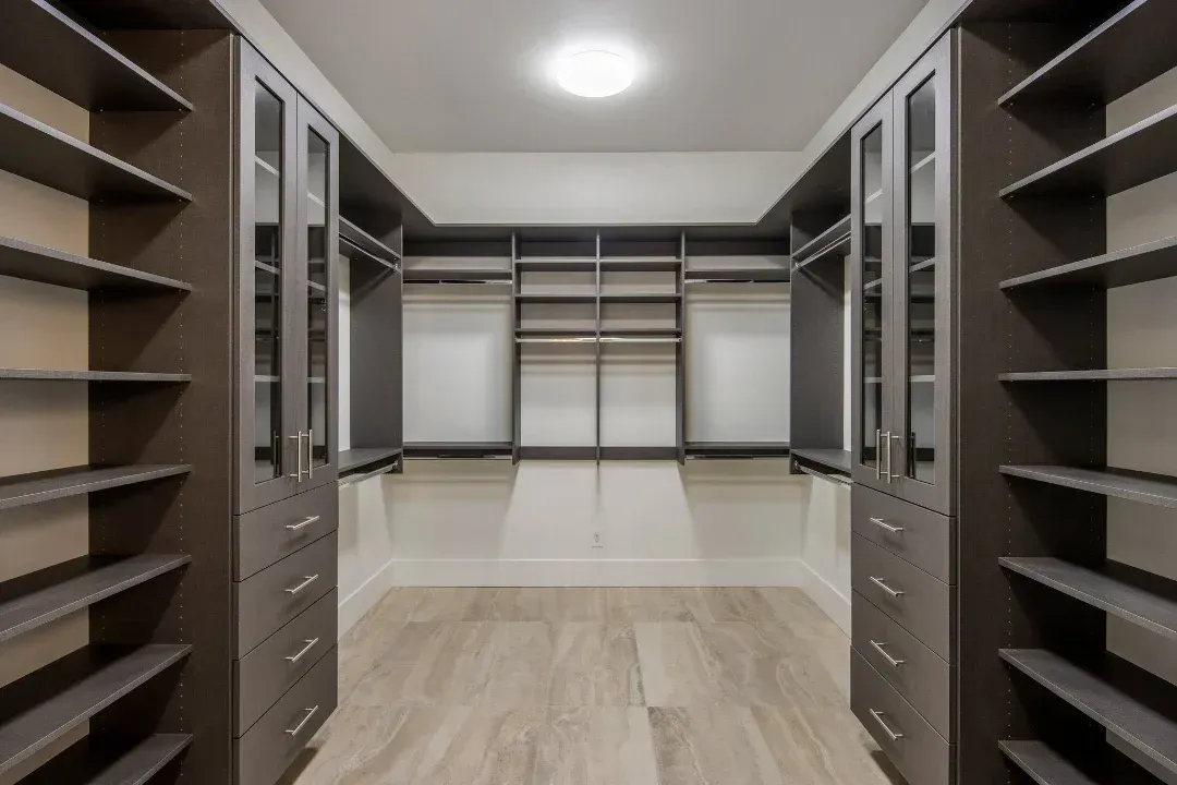 A walk in closet with lots of shelves and drawers.