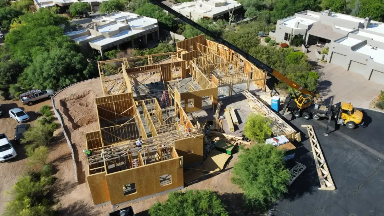 An aerial view of a house being built with a crane.