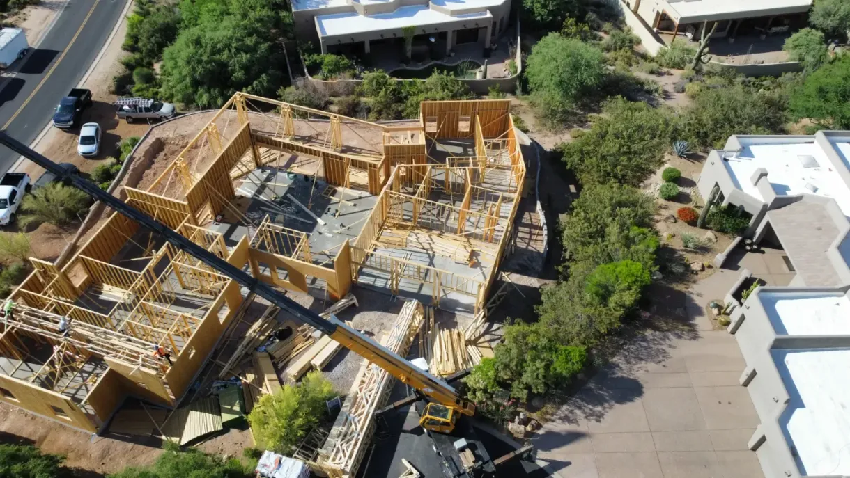 An aerial view of a house being built with a crane.