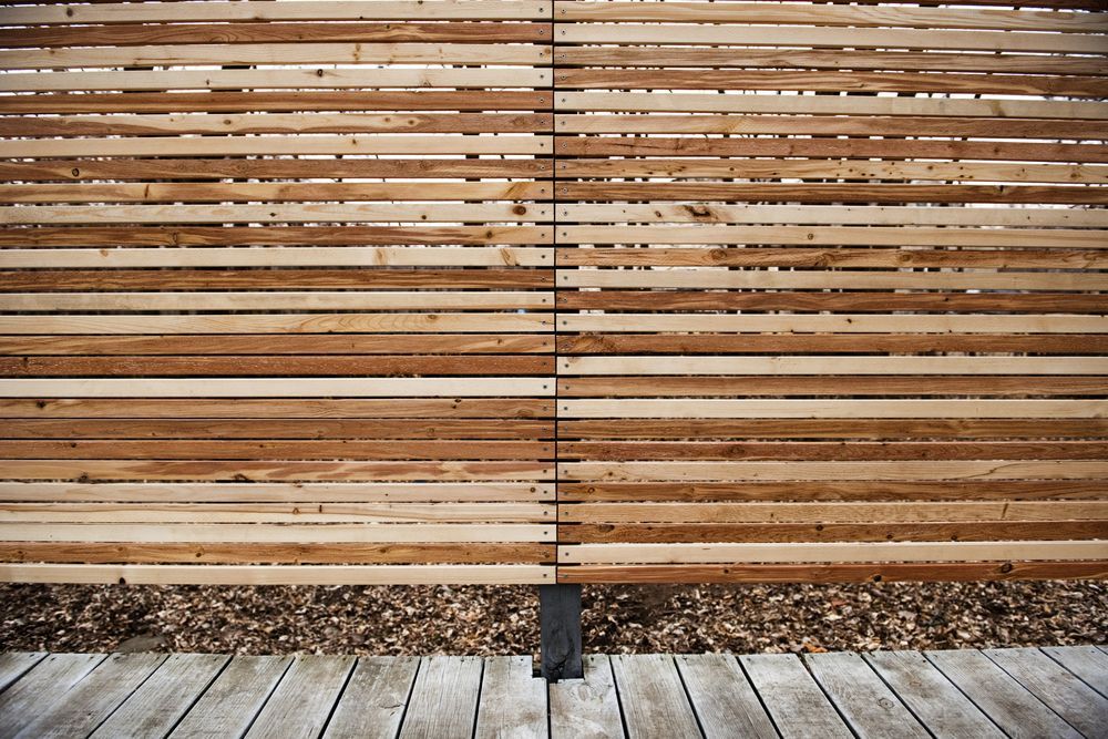 A Wooden Fence is Surrounded by Rocks and Grass in Front of a House — 2 Deadly Timber & Lattice in Ingham, QLD