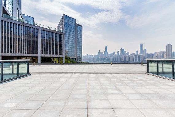 Empty rooftop terrace with glass railings and a city skyline in the distance