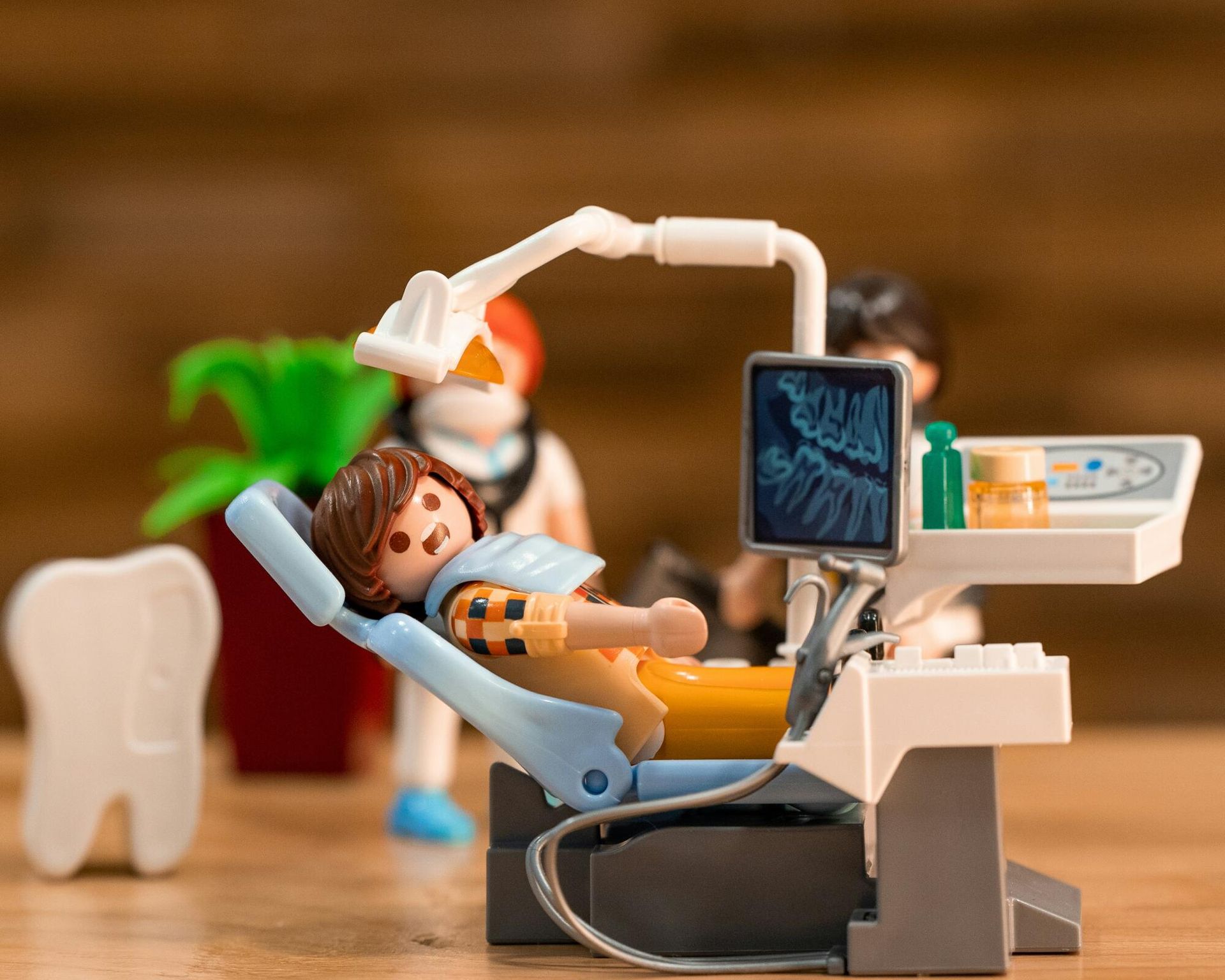 Playmobil dentist examining a patient in a blue chair with a dental X-ray screen.