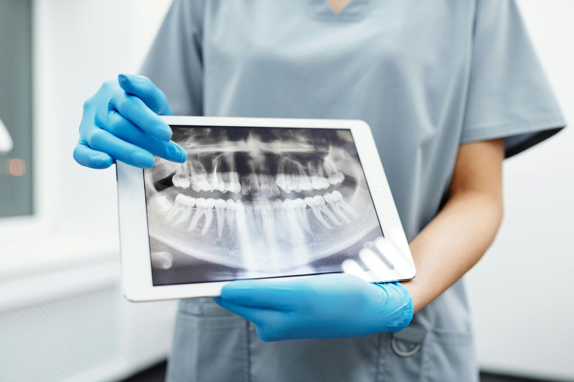 A dentist is holding a tablet with an x-ray of her teeth on it.
