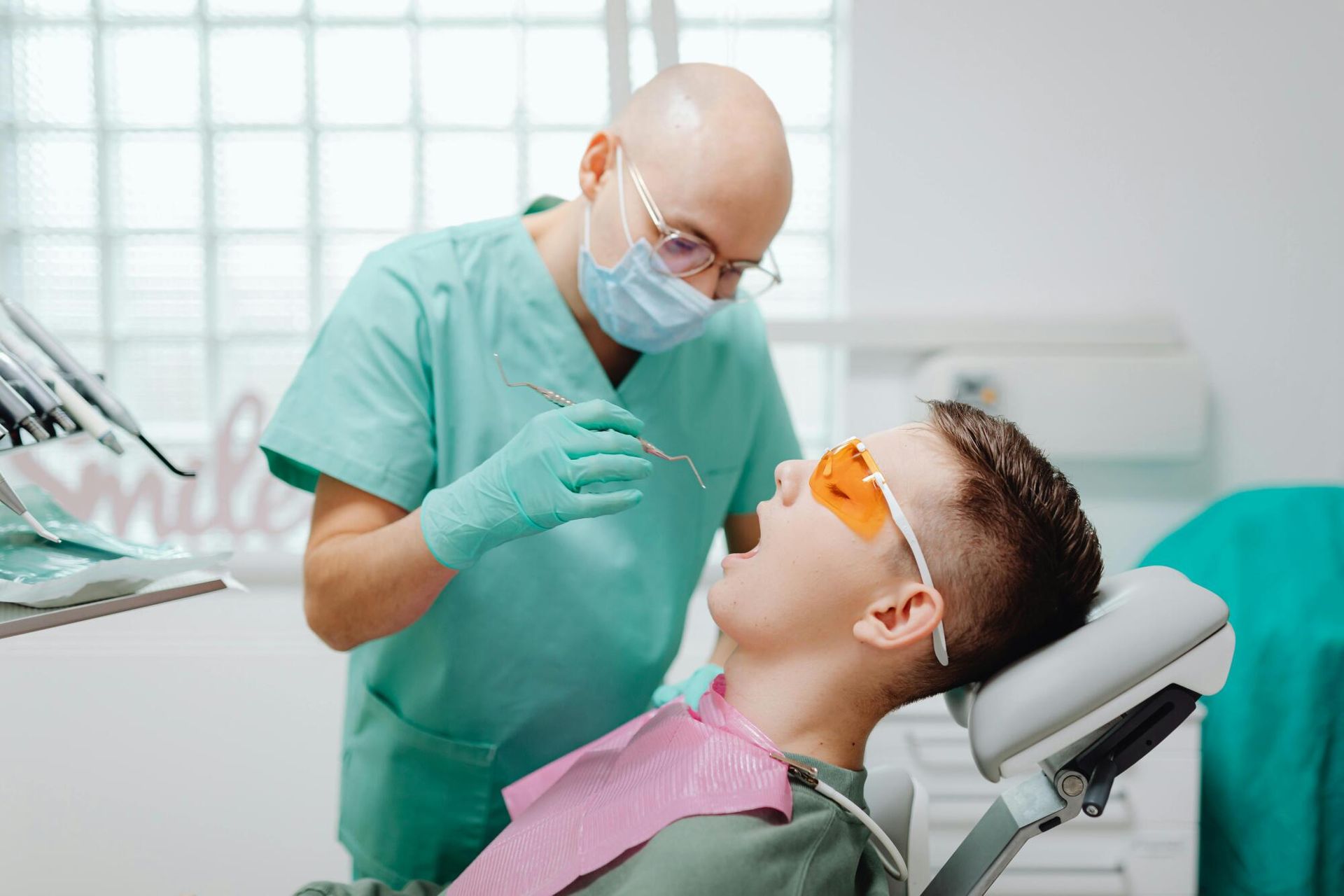 A man is sitting in a dental chair while a dentist examines his teeth.