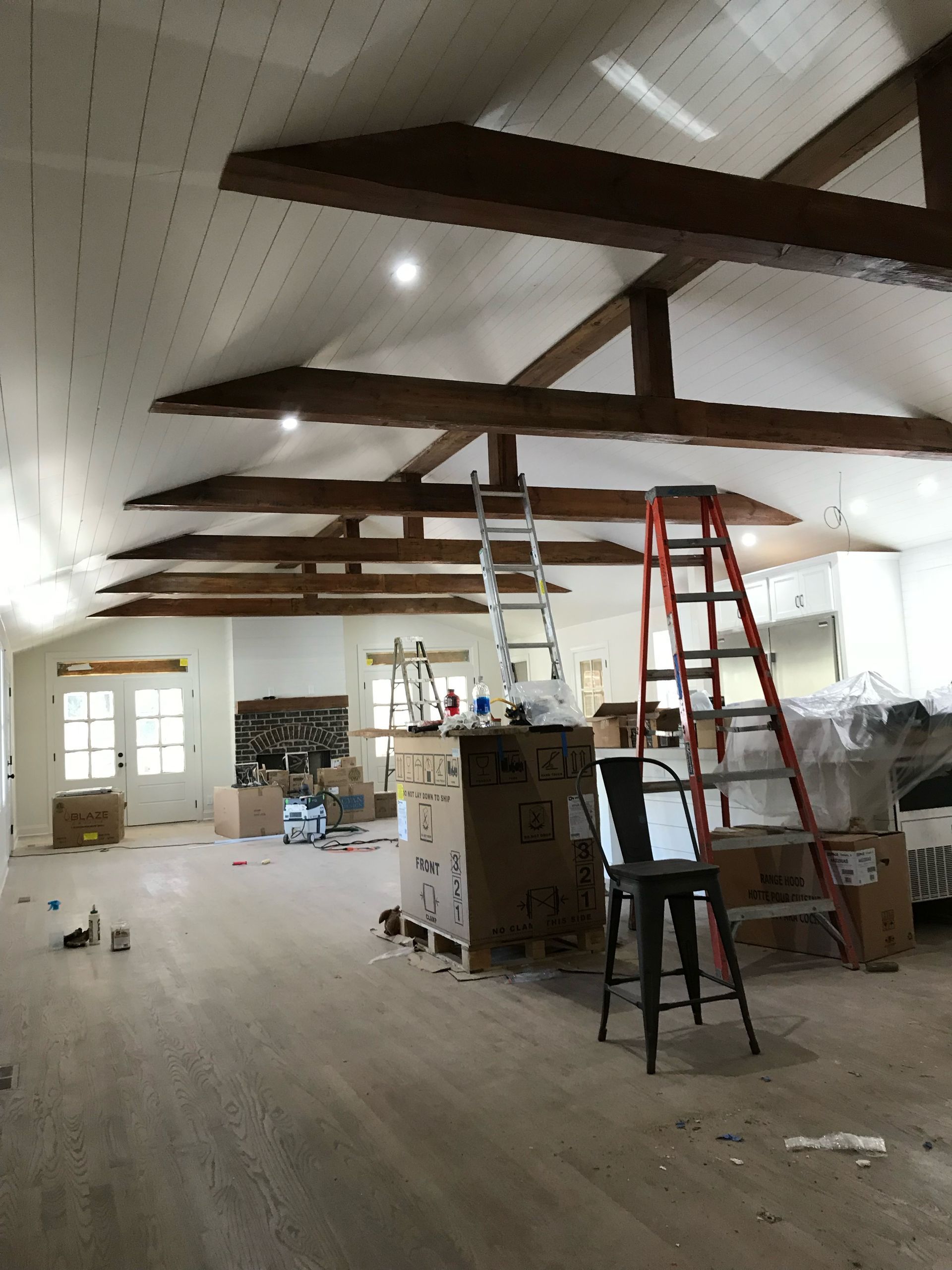 Man installing a recessed ceiling light in a modern kitchen with recessed lighting and glossy white cabinets.